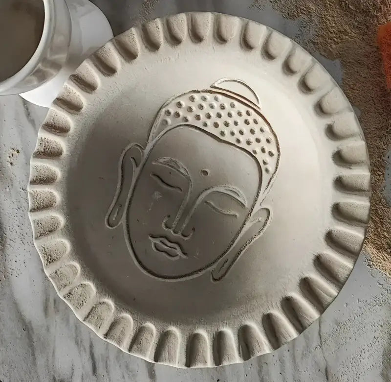 Sauberer Abdruck eines Buddha-Kopfes in einer runden Tonplatte. Beispiel für die präzise Linienführung des MinseArt Keramikstempels.
