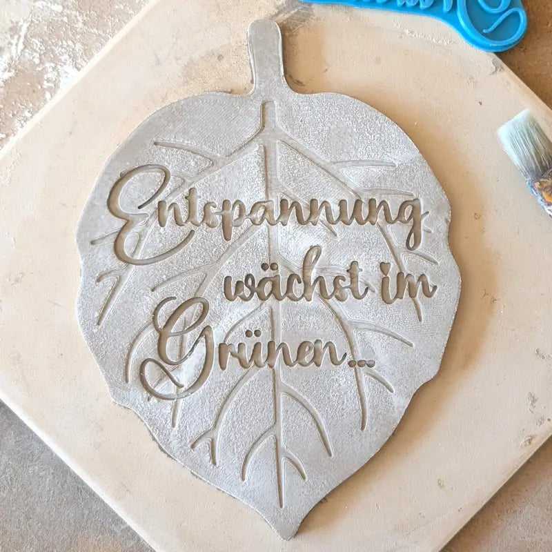Kreative Töpfer-Idee: Stempelabdruck 'Entspannung wächst im Grünen...' auf einer Tonplatte in Blattform. Handgefertigte Gartendeko, erstellt mit einem MinseArt Keramikstempel.