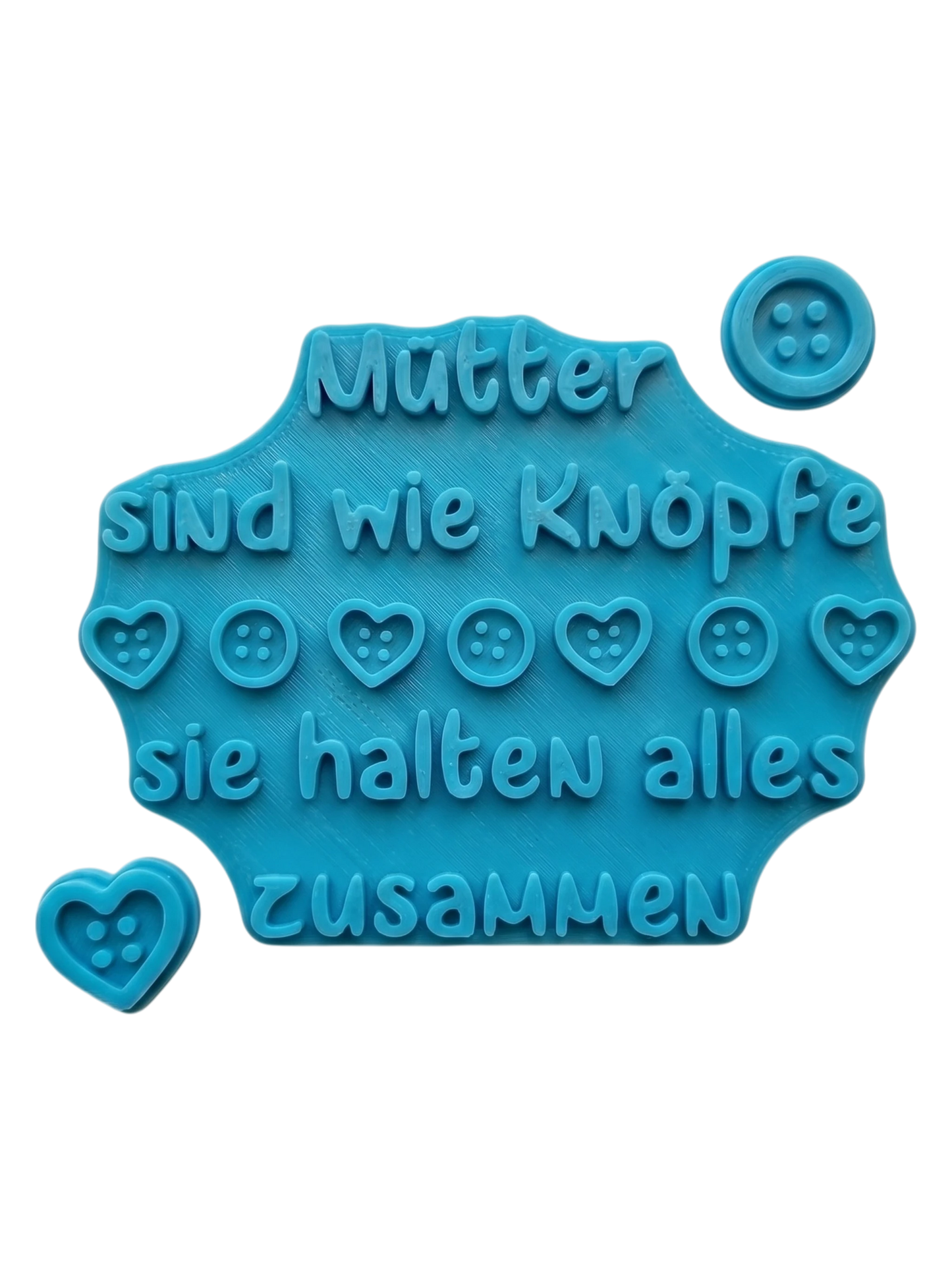 Blaugrüner Textstempel für Ton von MinseArt mit dem Spruch 'Mütter sind wie Knöpfe'. Hochwertiges Töpferwerkzeug inklusive passender Motivstempel (Herz & Knopf) für tiefe Prägungen in Keramik. Ideal für handgemachte Muttertagsgeschenke.