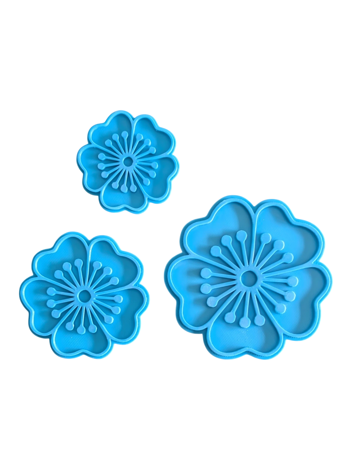 Detailansicht der drei blauen floralen Keramikstempel nebeneinander zur Verdeutlichung der Prägetiefe.