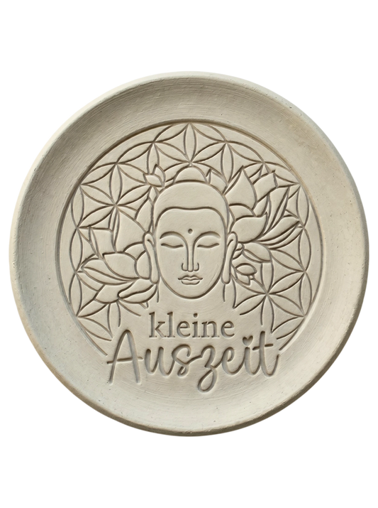 Detailreicher Stempelabdruck eines Buddhas mit Lotusblüten und dem Schriftzug 'kleine Auszeit' in hellem Ton. Präzise Konturen für meditative Töpfer-Projekte.