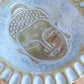 Glasierter Keramikteller mit Buddha-Motiv. Die hellgelbe Glasur betont die Vertiefungen des Stempelabdrucks und zeigt das fertige Ergebnis.