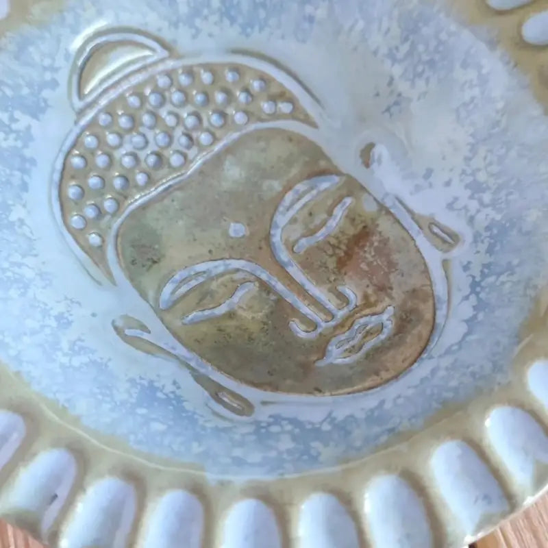 Glasierter Keramikteller mit Buddha-Motiv. Die hellgelbe Glasur betont die Vertiefungen des Stempelabdrucks und zeigt das fertige Ergebnis.
