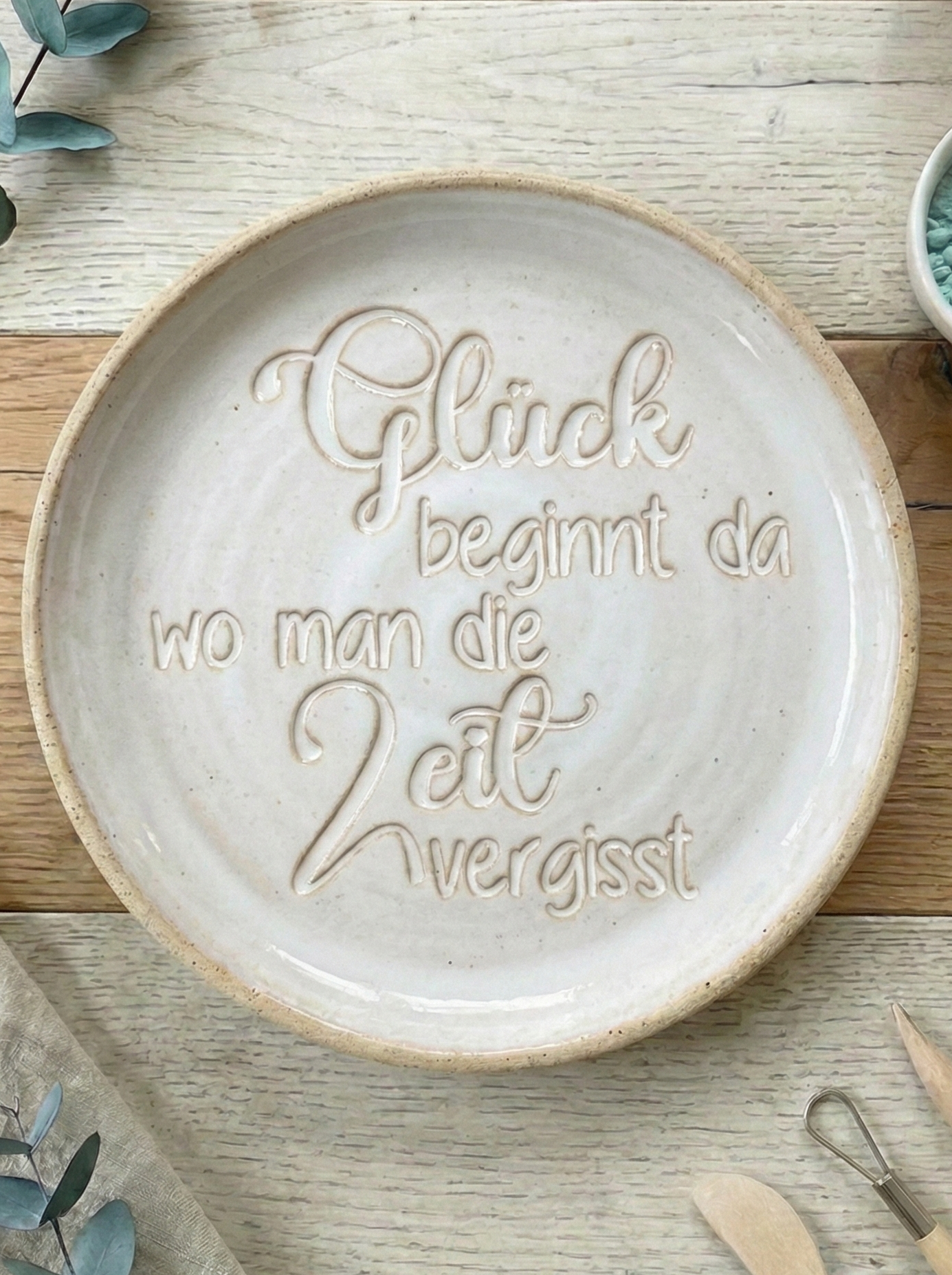 Ein fertig glasiertes Keramikschälchen mit dem eingestempelten Spruch 'Glück beginnt da, wo man die Zeit vergisst'. Die helle Glasur betont das tiefe Relief des MinseArt Textstempels.