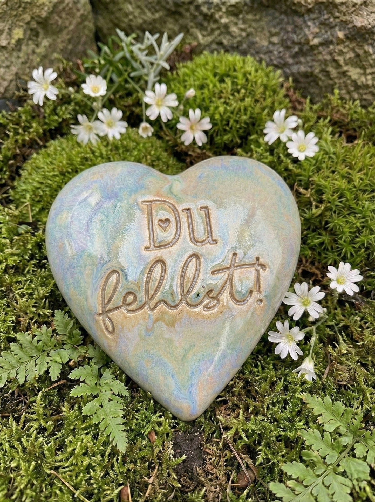 Handgemachtes Keramikherz mit dem eingestempelten Text 'Du fehlst!'. Der saubere Abdruck des Keramikstempels kommt durch die Glasur wunderschön zur Geltung. Liebevoller Grabschmuck, gebettet auf Moos und weißen Blüten.