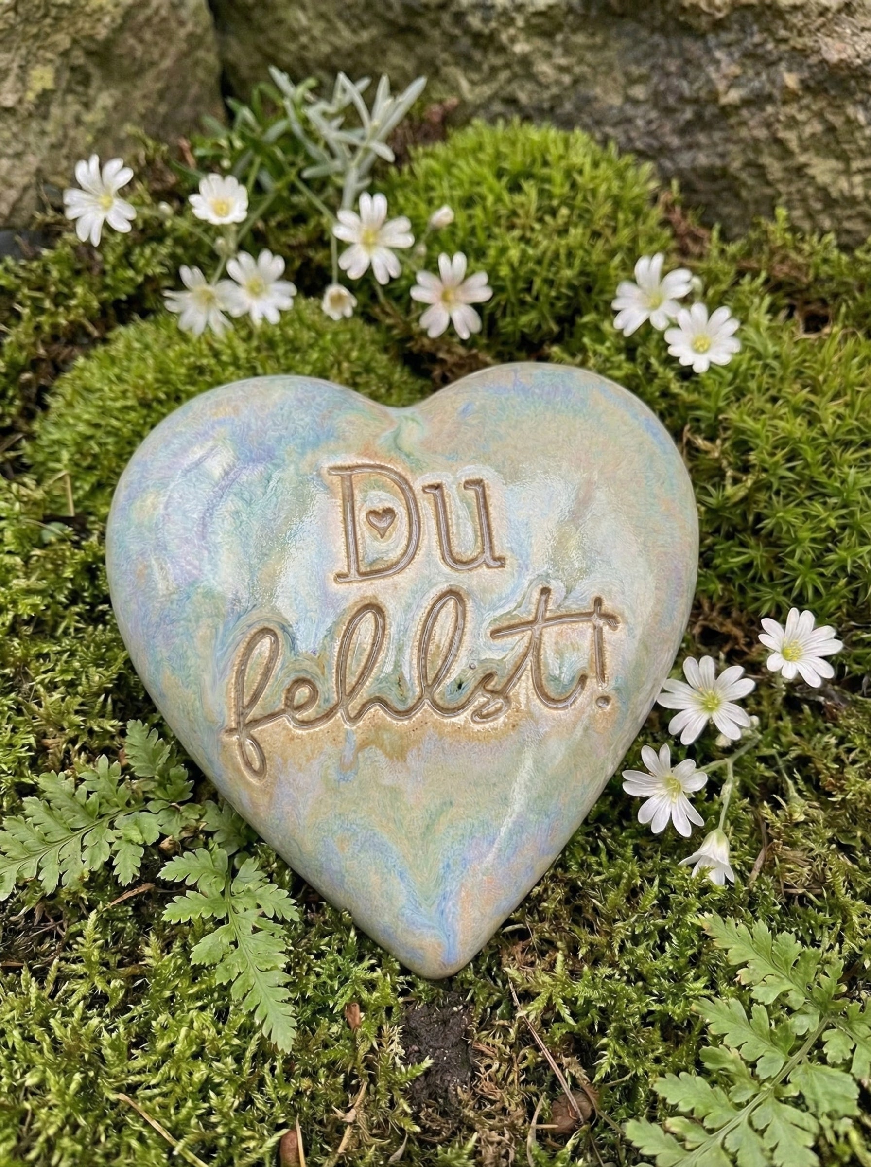 Handgemachtes Keramikherz mit dem eingestempelten Text 'Du fehlst!'. Der saubere Abdruck des Keramikstempels kommt durch die Glasur wunderschön zur Geltung. Liebevoller Grabschmuck, gebettet auf Moos und weißen Blüten.