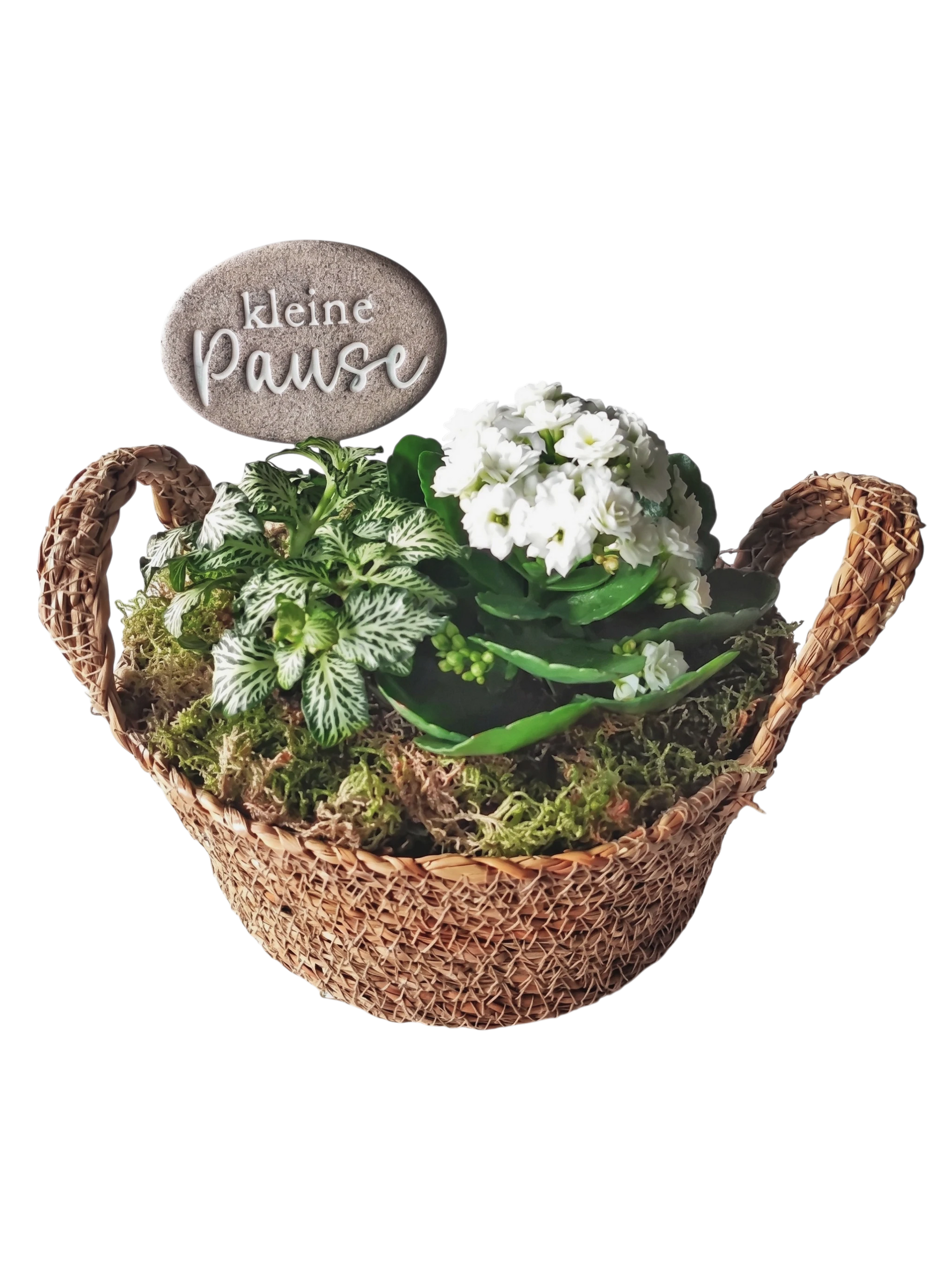 Ein handgemachter, ovaler Keramikstecker mit dem Spruch 'kleine Pause', weiß akzentuiert, steckt in einem geflochtenen Weidenkörbchen mit grünen Pflanzen und weißen Blüten. Eine kreative Töpfer-Idee von MinseArt.