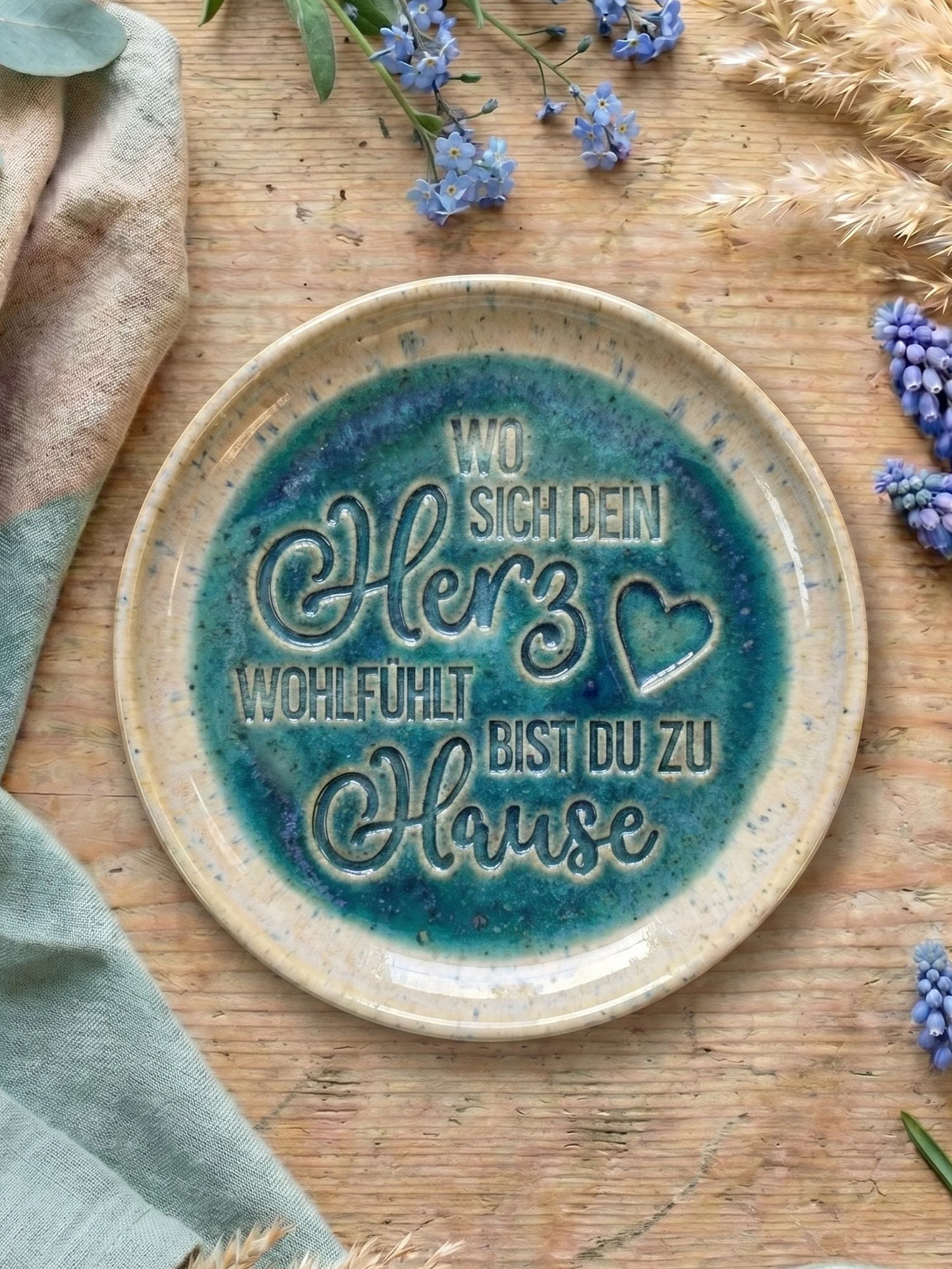 Fertig glasierter Keramikteller in Blaugrün mit dem eingestempelten Spruch 'Wo sich dein Herz wohlfühlt bist du zu Hause'. Eine inspirierende Töpfer-Idee für das eigene Heim. Die saubere Schrift wurde mit einem MinseArt Textstempel für Ton gefertigt.