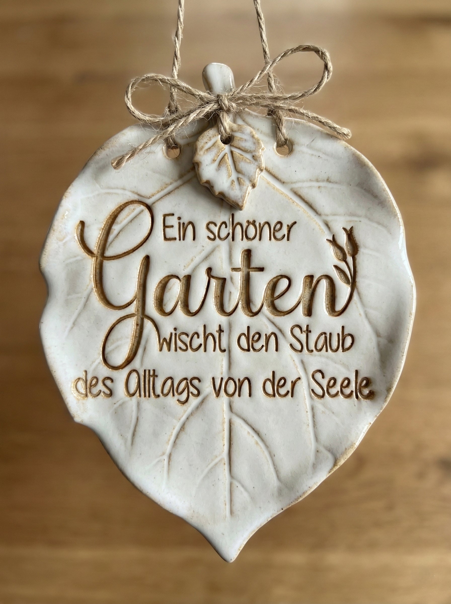 Glasiertes Keramikschild in Blattform mit dem eingestempelten Spruch 'Ein schöner Garten wischt den Staub des Alltags von der Seele'. Handgemachte Töpfer-Idee für stilvolle Gartendeko.