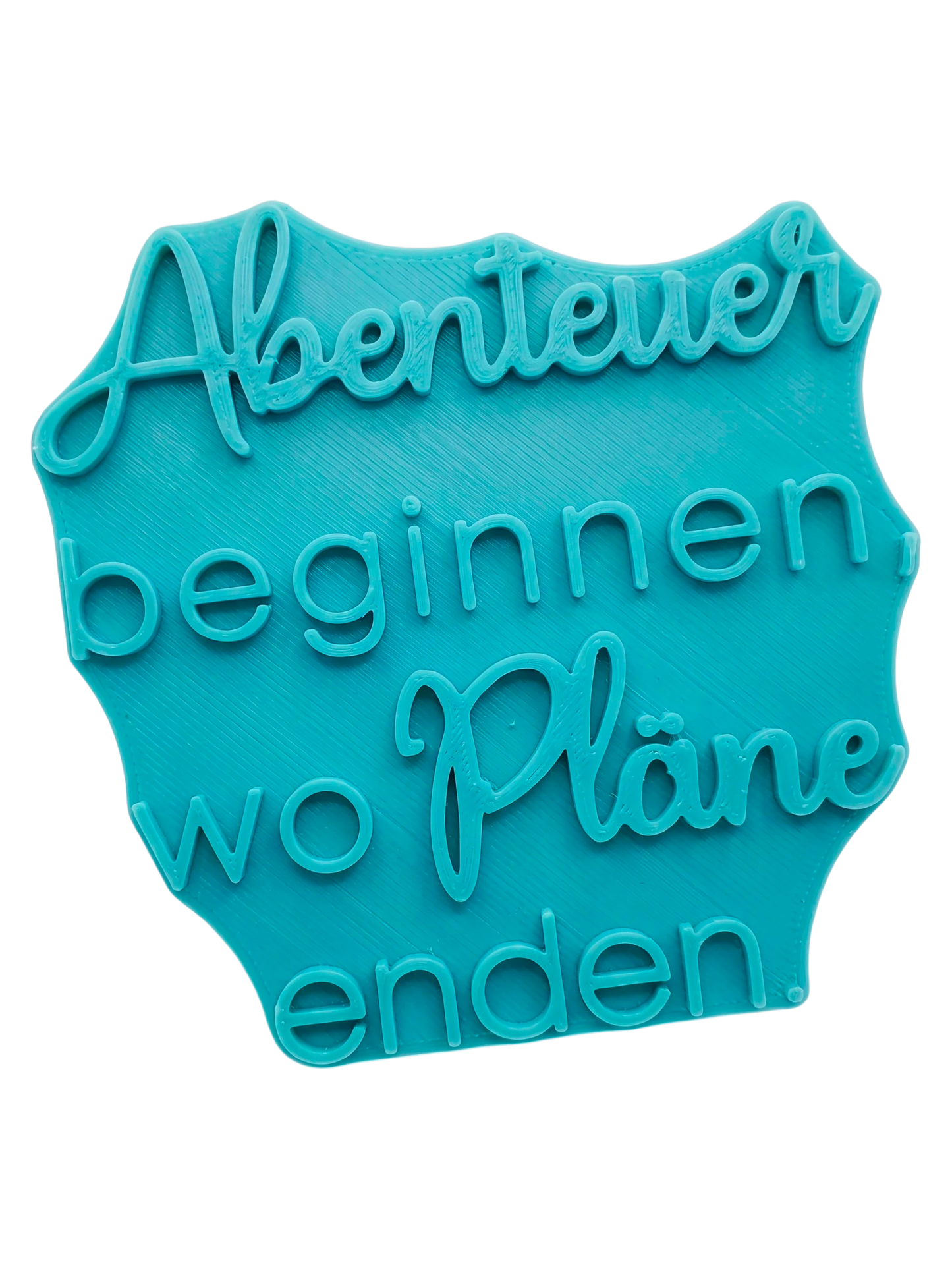 Türkisfarbener Keramikstempel mit dem Spruch 'Abenteuer beginnen, wo Pläne enden'. Hochwertiges Töpferwerkzeug für saubere Textprägungen in Ton.