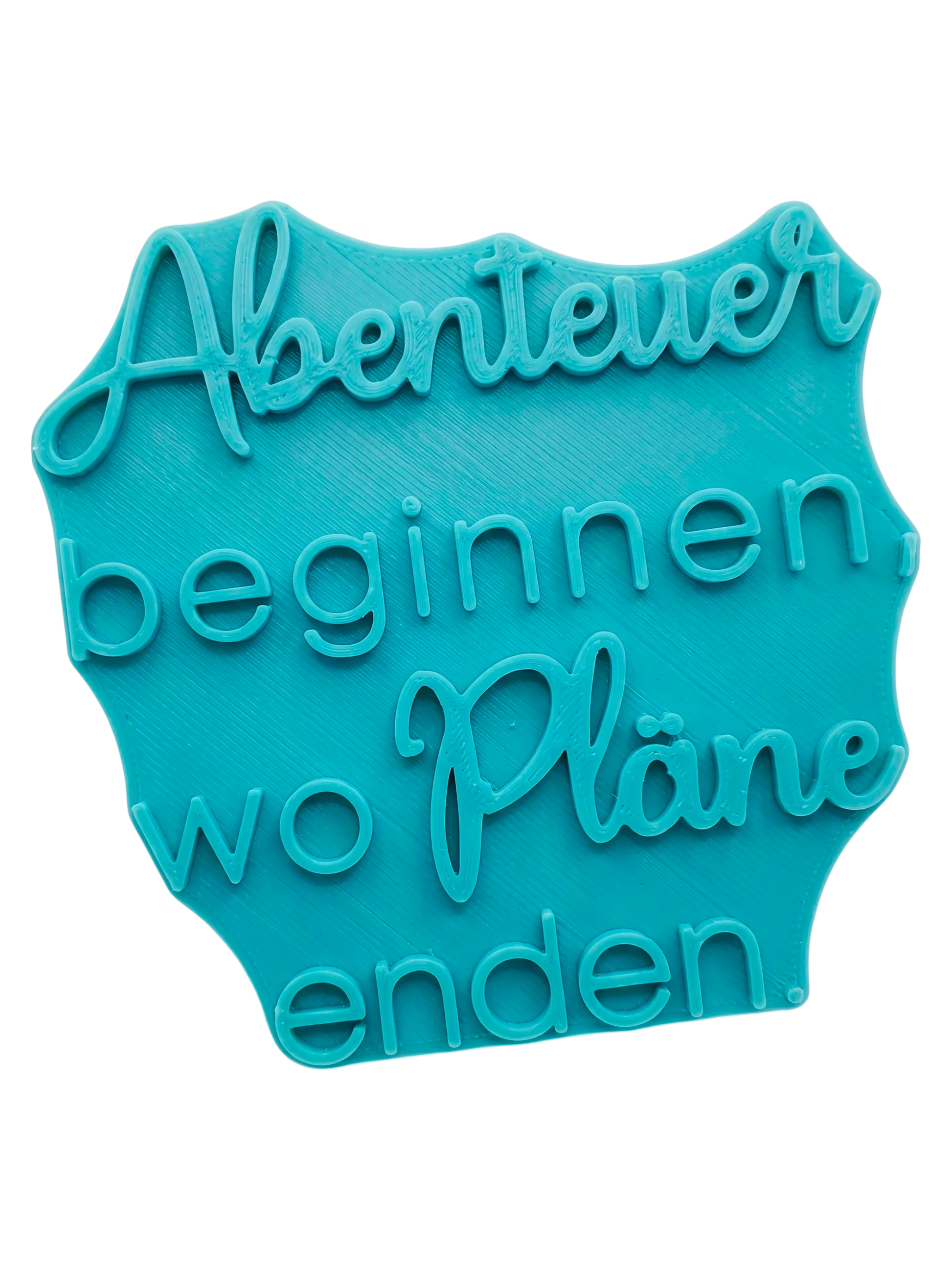 Türkisfarbener Keramikstempel mit dem Spruch 'Abenteuer beginnen, wo Pläne enden'. Hochwertiges Töpferwerkzeug für saubere Textprägungen in Ton.