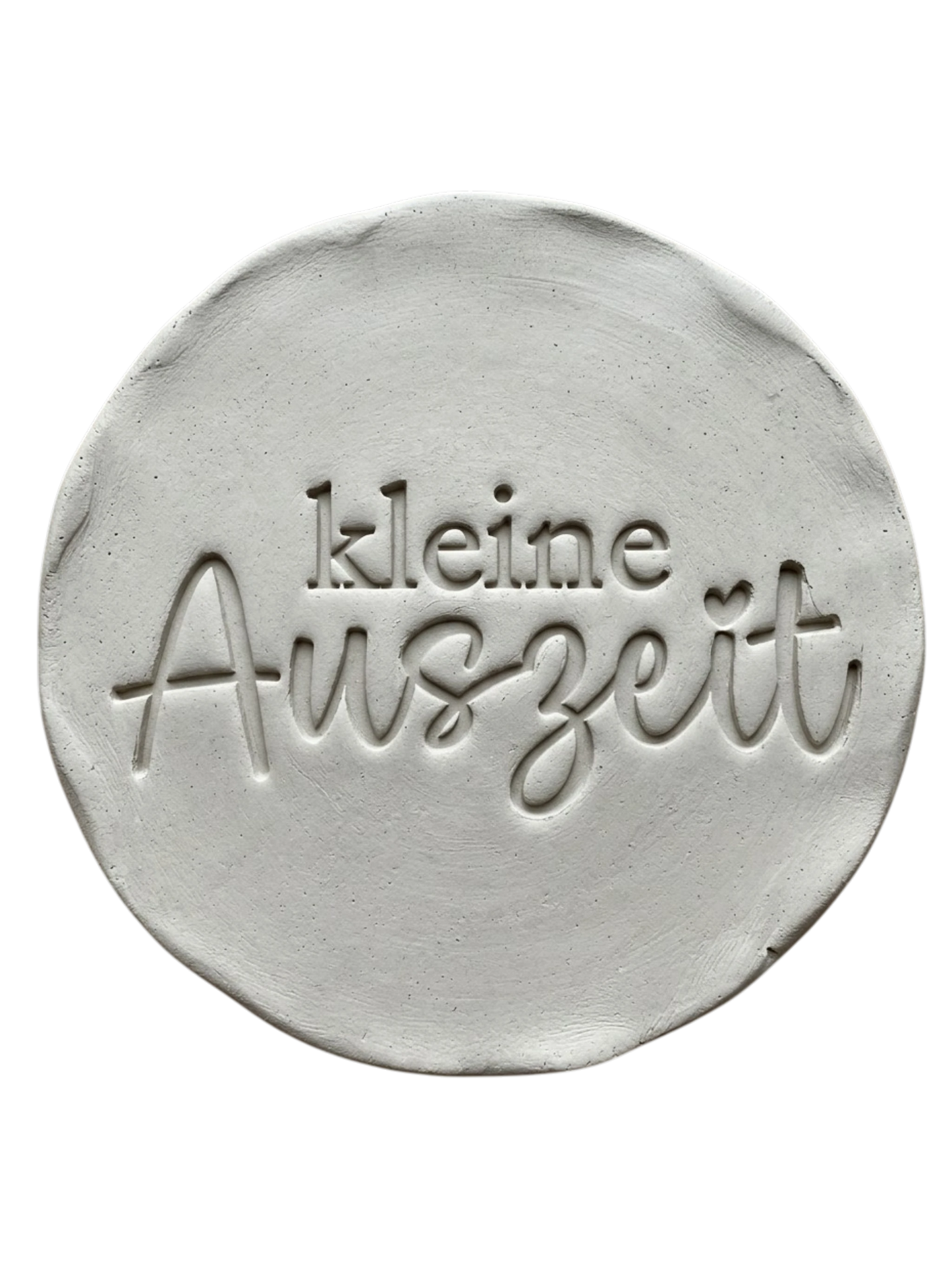 Präziser Stempelabdruck 'kleine Auszeit' in hellem Ton. Das saubere Relief kombiniert eine moderne Serifenschrift mit eleganter Schreibschrift auf einer runden Tonplatte.