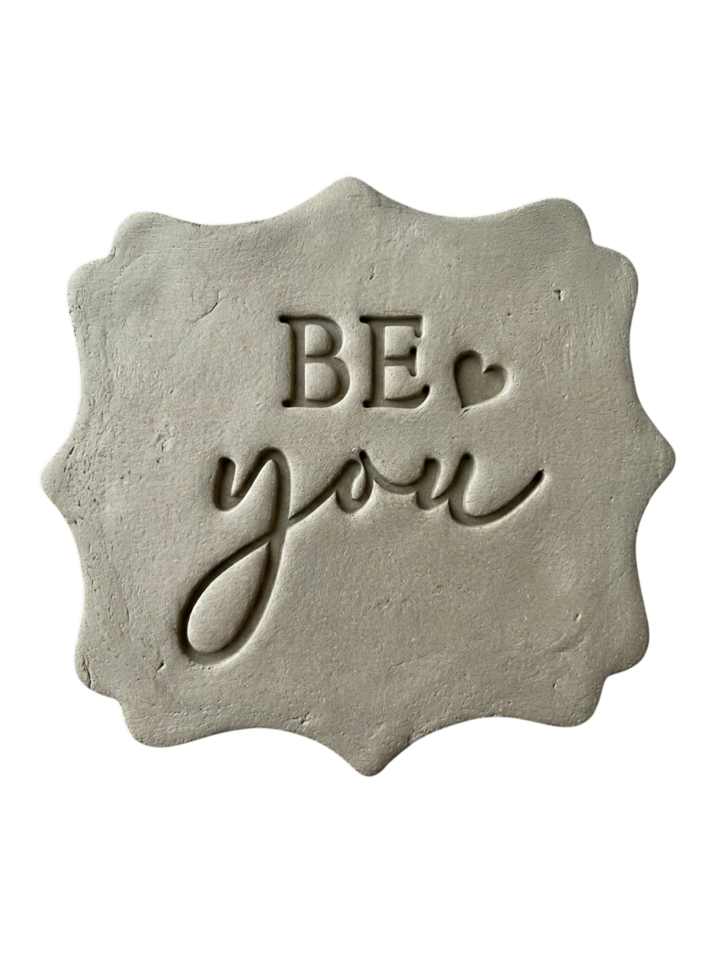 Präziser Abdruck im hellen Ton mit der Botschaft 'BE you' auf einer dekorativ geformten Tonplatte. Kreative Töpfer-Idee für Motivations-Schilder oder Wand-Deko.