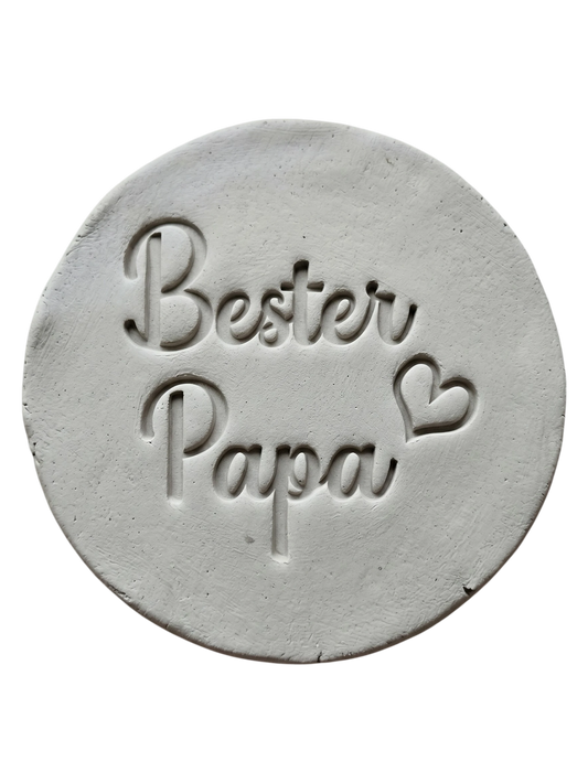 Handgemachte Töpfer-Idee zum Vatertag: Ein mit dem MinseArt Keramikstempel geprägter Ton-Anhänger 'Bester Papa' mit Herz. Präziser Abdruck in hellem Ton, ideal für DIY-Geschenke und persönliche Keramik-Projekte.