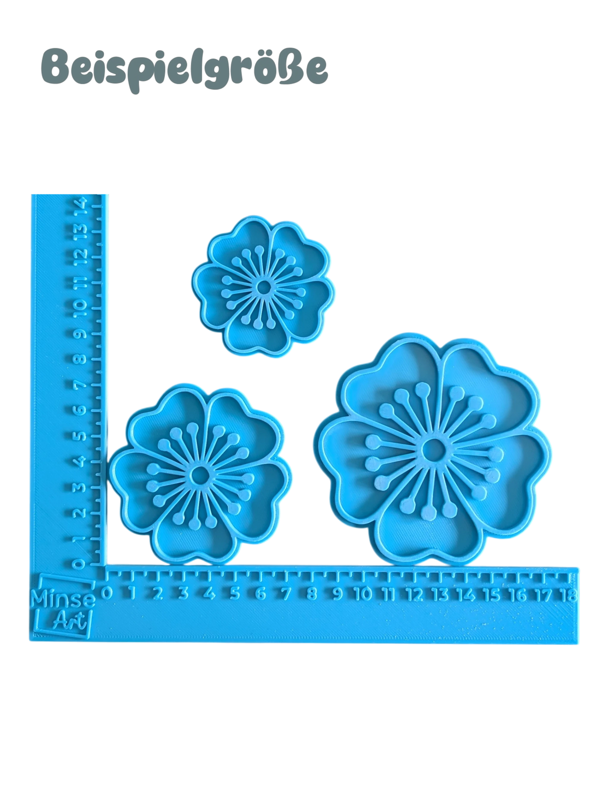 Drei blaue Keramikstempel mit Blumen-Motiven angelegt an ein Maßband-Winkelwerkzeug zur Darstellung der Größen 5,5 cm, 7 cm und 9 cm.