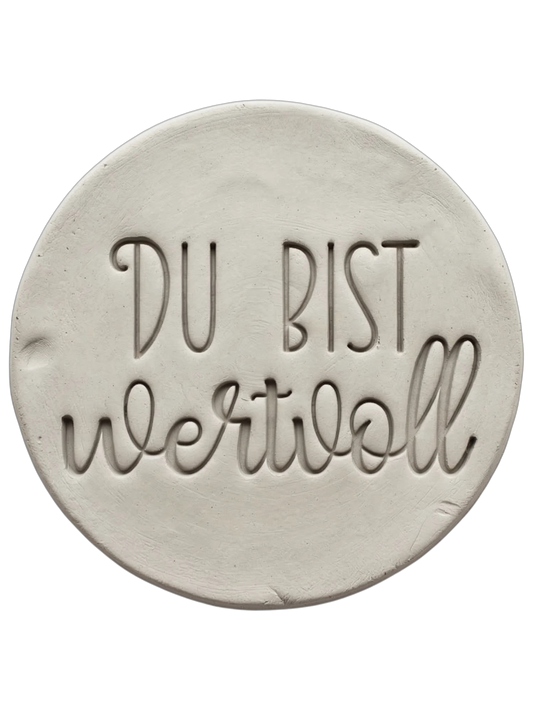 Sauberer Stempelabdruck im hellen Ton mit dem Schriftzug 'DU BIST wertvoll'. Kombination aus moderner Druckschrift und eleganter Schreibschrift, erstellt mit einem MinseArt Keramikstempel.