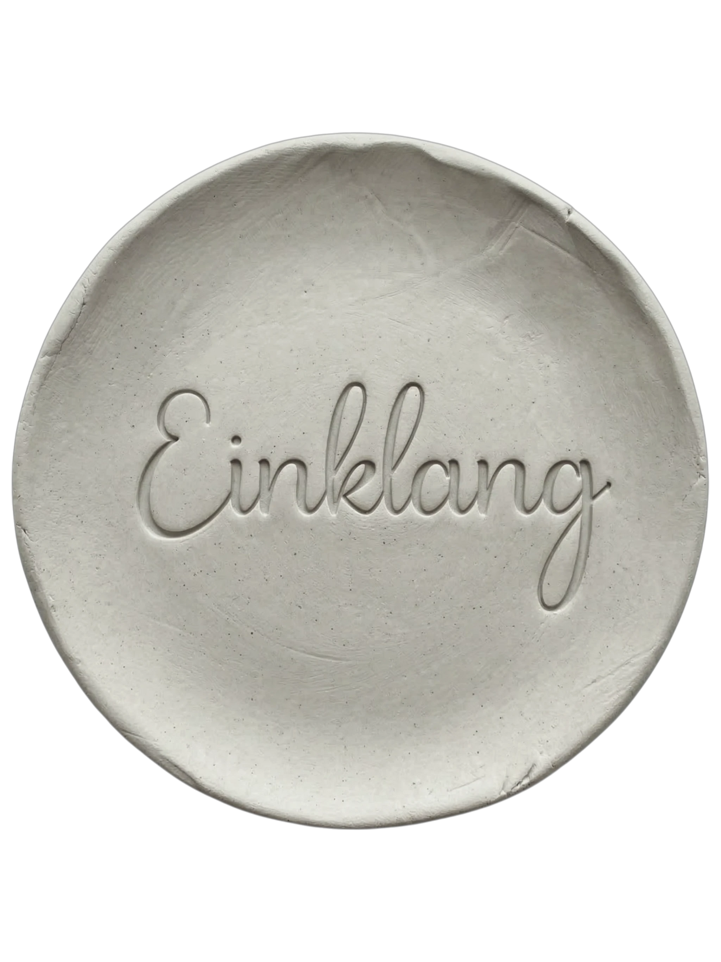 Präziser Stempelabdruck des Wortes 'Einklang' in eleganter Schreibschrift auf einer runden Tonplatte. Filigranes Relief für spirituelle Keramik, gestaltet mit einem MinseArt Keramikstempel.