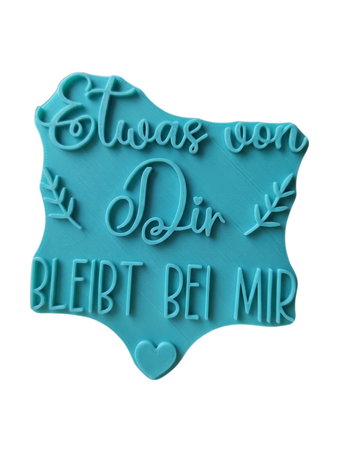 Draufsicht auf den türkisfarbenen Keramikstempel 'Etwas von dir bleibt bei mir' mit kleinen Blättern und Herz. Ein detailreicher Textstempel und Tonstempel für liebevolle Erinnerungsstücke.