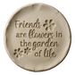 Detailreicher Abdruck im hellen Ton mit dem Spruch 'Friends are flowers in the garden of life' und geprägten Blumen. Kreative Töpfer-Idee für Freundschaftsgeschenke oder Dekoration