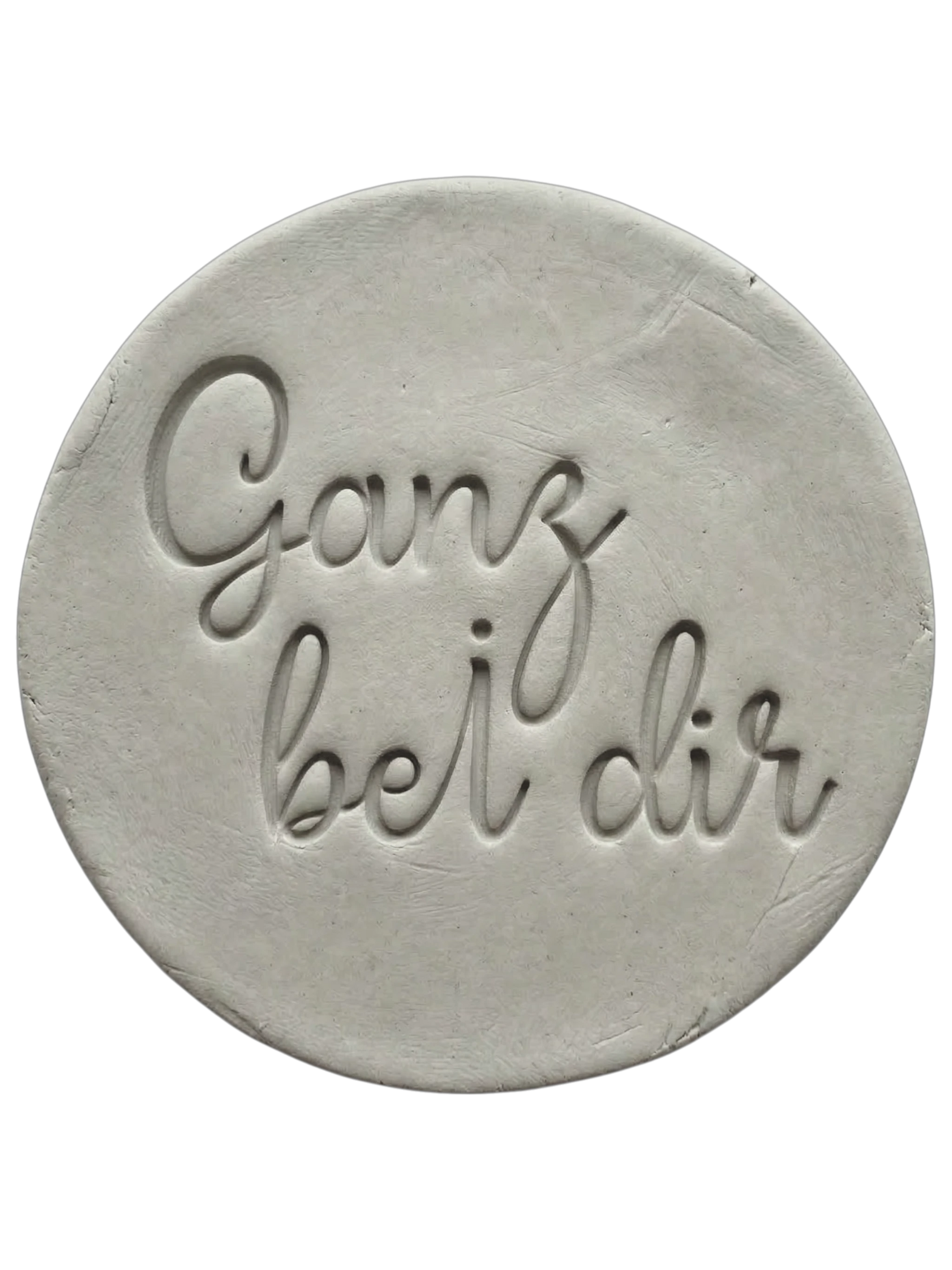 Filigraner Stempelabdruck in eleganter Handschrift mit dem Spruch 'Ganz bei dir' auf einer runden Tonplatte. Sauberes Relief-Ergebnis für meditative Keramik, gestaltet mit einem MinseArt Keramikstempel.