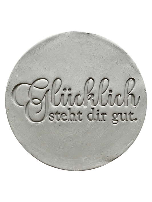Sauberer Stempelabdruck des Spruchs 'Glücklich steht dir gut' in hellem Ton. Die Kombination aus eleganter Schreibschrift und klarer Druckschrift erzeugt ein präzises Relief.