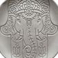Detailreicher Abdruck einer Hamsa Hand mit Ganesha in einer runden Tonplatte. Präzises Relief für die Gestaltung von Schutzsymbolen aus Keramik.