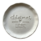 Sauberer Abdruck im hellen Ton mit dem Spruch 'Heimat Liebe'. Kreative Töpfer-Idee für regionale Wandteller, Türschilder oder rustikale Deko.