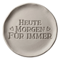 Präziser Stempelabdruck des romantischen Spruchs 'Heute Morgen Für Immer' in hellem Ton. Detailreiches, sauberes Relief in klassischer Druckschrift mit kleinen Herzen auf einer runden Tonplatte.