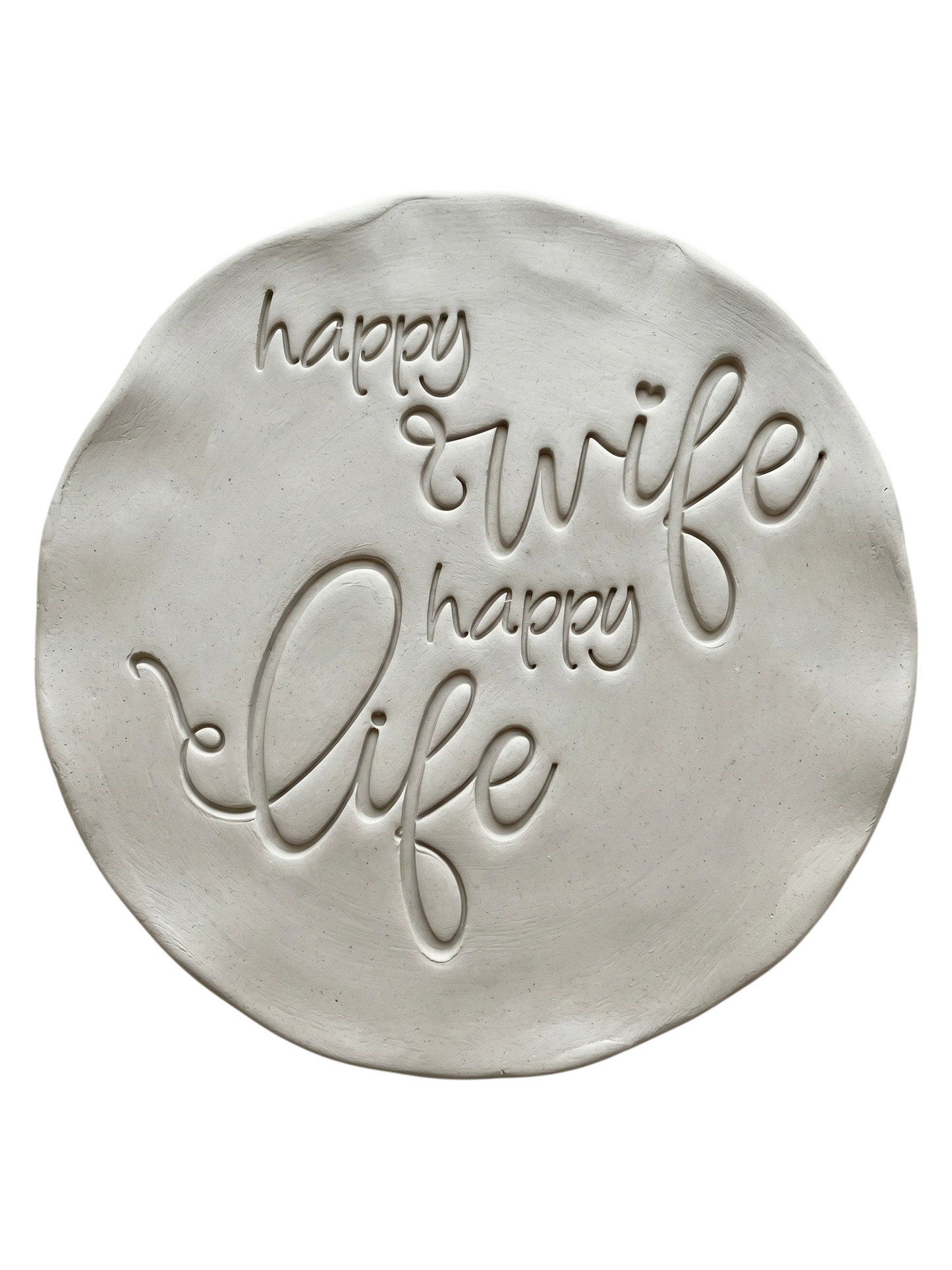 Präziser Stempelabdruck 'happy wife happy life' in hellem Ton. Die schwungvolle, moderne Schreibschrift erzeugt ein sauberes, tiefes Relief auf der runden Tonplatte.
