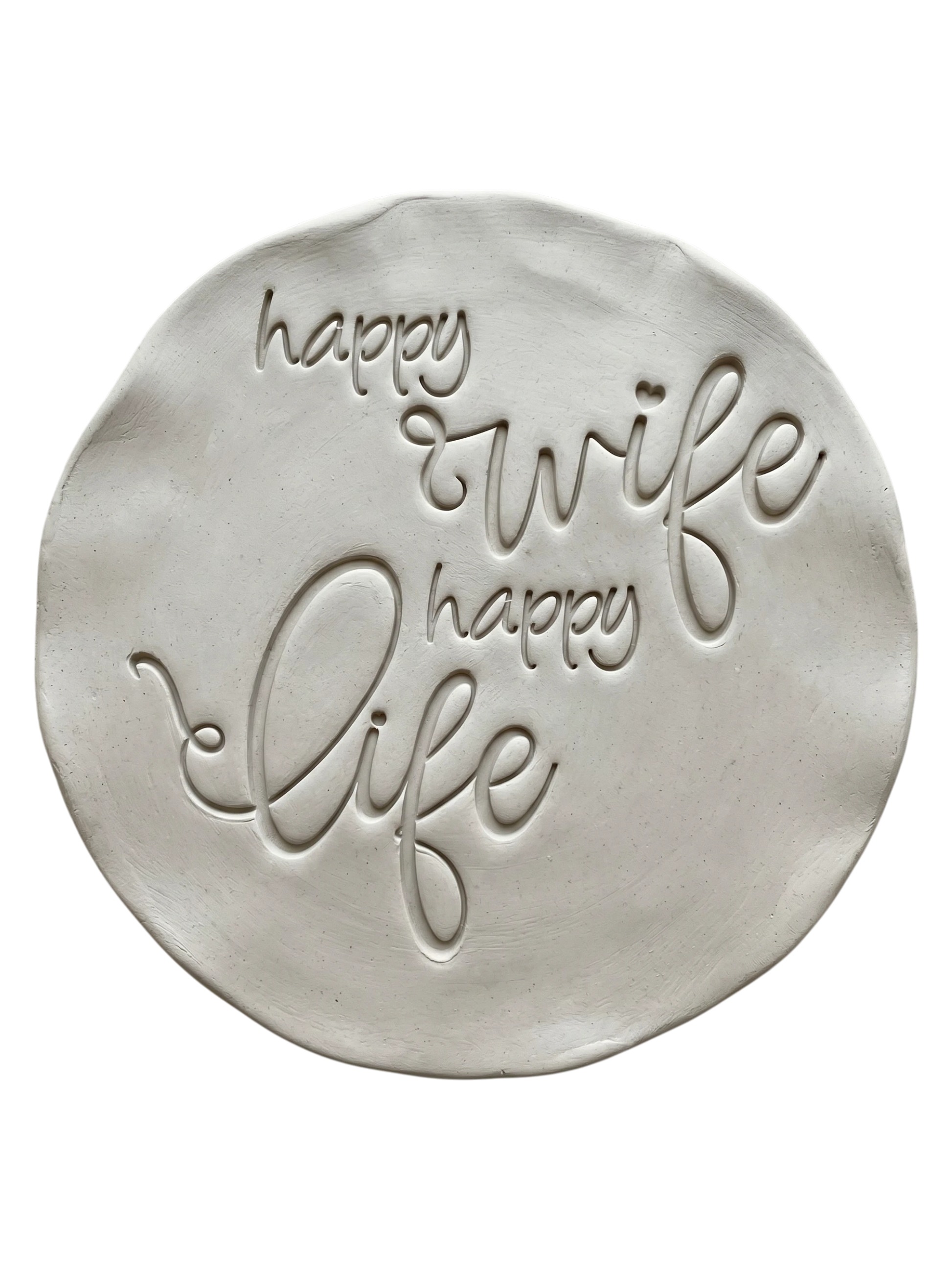 Präziser Stempelabdruck 'happy wife happy life' in hellem Ton. Die schwungvolle, moderne Schreibschrift erzeugt ein sauberes, tiefes Relief auf der runden Tonplatte.