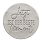 Präziser Stempelabdruck 'Jetzt ist der beste Moment' in hellem Ton. Die harmonische Kombination aus schwungvoller Kalligrafie und klarer Serifenschrift erzeugt ein tiefes Relief.