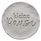 Präziser Stempelabdruck 'kleine Pause' in hellem Ton. Die Kombination aus moderner Druckschrift und eleganter Schreibschrift erzeugt ein sauberes Relief auf der runden Tonplatte.