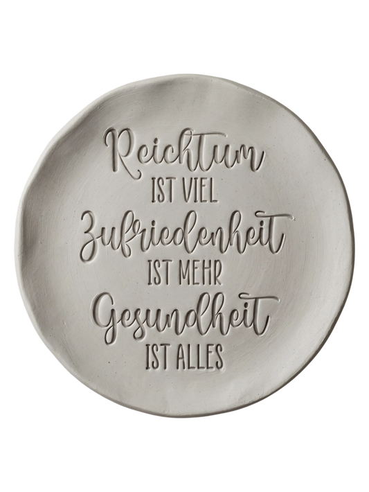 Präziser Stempelabdruck einer Lebensweisheit in hellem Ton. Die harmonische Kombination aus Schreibschrift und Druckschrift erzeugt ein sauberes, tiefes Relief auf der runden Tonplatte.