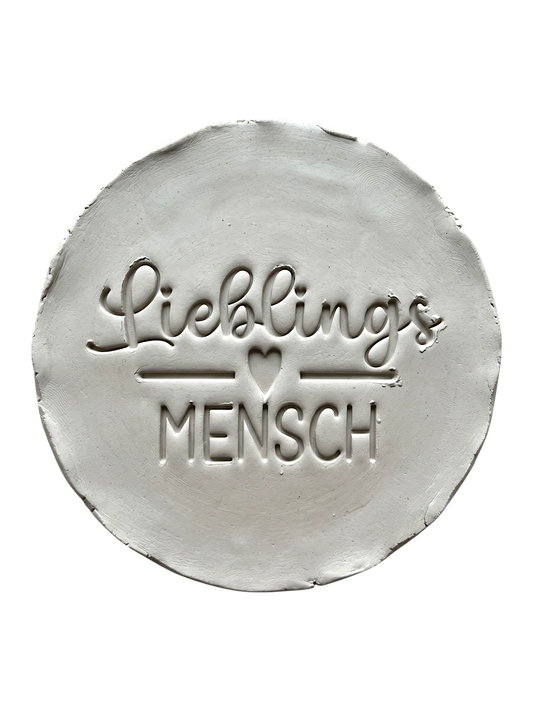 Präziser Abdruck im hellen Ton mit dem Schriftzug 'Lieblingsmensch'. Kreative Töpfer-Idee für persönliche Geschenke, Anhänger oder Wandteller.