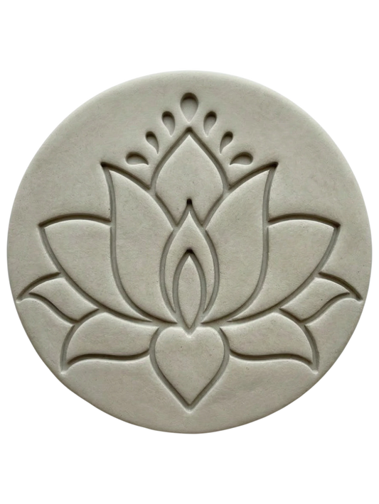 Ein präziser Stempelabdruck einer modernen Lotusblüte in einer runden, hellgrauen Tonplatte. Das minimalistische Design mit klaren Linien und zwei Punkten über der Blüte zeigt die tiefe Relief-Wirkung der MinseArt Keramikstempel.
