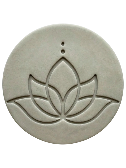 Ein präziser Stempelabdruck einer modernen Lotusblüte in einer runden, hellgrauen Tonplatte. Das minimalistische Design mit klaren Linien und zwei Punkten über der Blüte zeigt die tiefe Relief-Wirkung der MinseArt Keramikstempel.