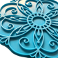Nahaufnahme des türkisfarbenen Keramikstempels mit floralem Mandala-Muster. Der detailreiche Prägestempel zeigt feine Linien und Bögen für perfekte Abdrücke im Ton.