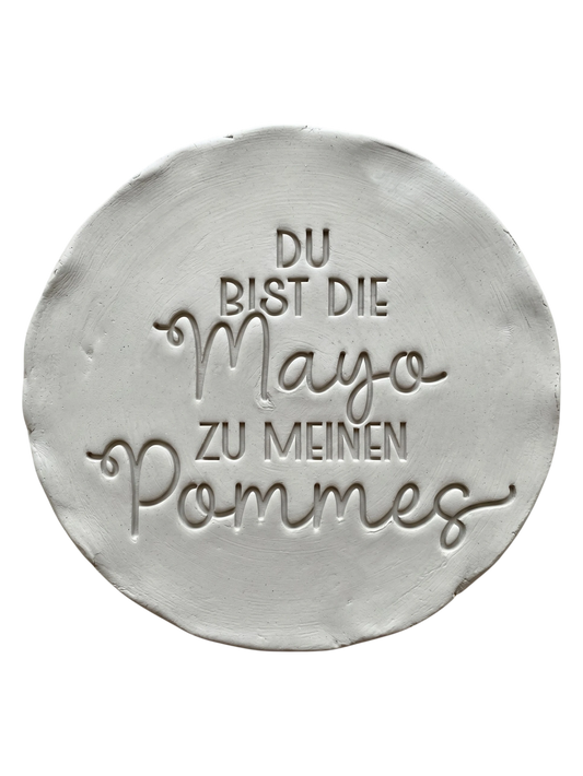 Präziser Stempelabdruck des humorvollen Spruchs 'Du bist die Mayo zu meinen Pommes' in hellem Ton. Detailreiches und sauberes Relief auf einer runden Tonplatte für handgemachte Keramik.