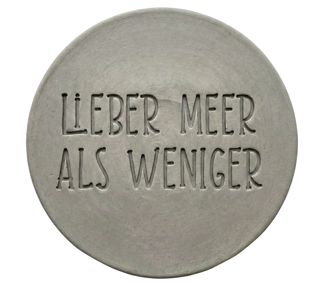 Klarer und tiefer Stempelabdruck des Textes 'Lieber Meer als weniger' auf einer runden, hellen Tonplatte. Ein perfektes Ergebnis für das nächste Töpferprojekt.