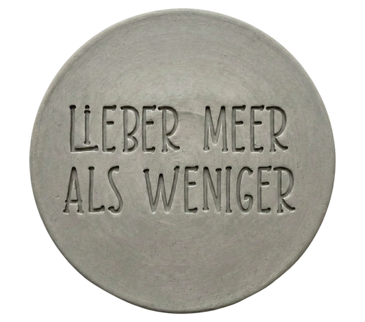 Klarer und tiefer Stempelabdruck des Textes 'Lieber Meer als weniger' auf einer runden, hellen Tonplatte. Ein perfektes Ergebnis für das nächste Töpferprojekt.