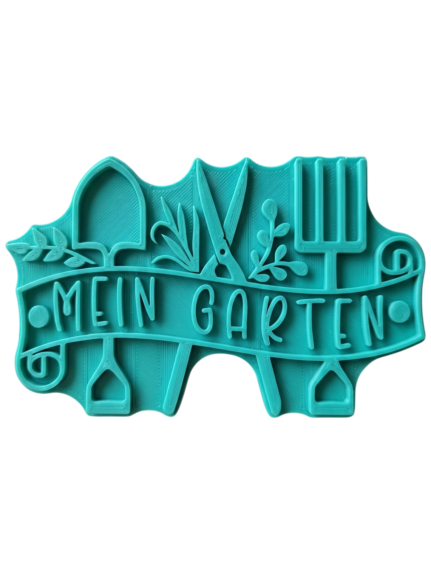 Türkisfarbener Keramikstempel für Ton mit dem Schriftzug 'Mein Garten' auf einem Banner, umrahmt von Schaufel, Gartenschere und Grabegabel. Detailreicher Prägestempel für kreative Töpfer-Ideen