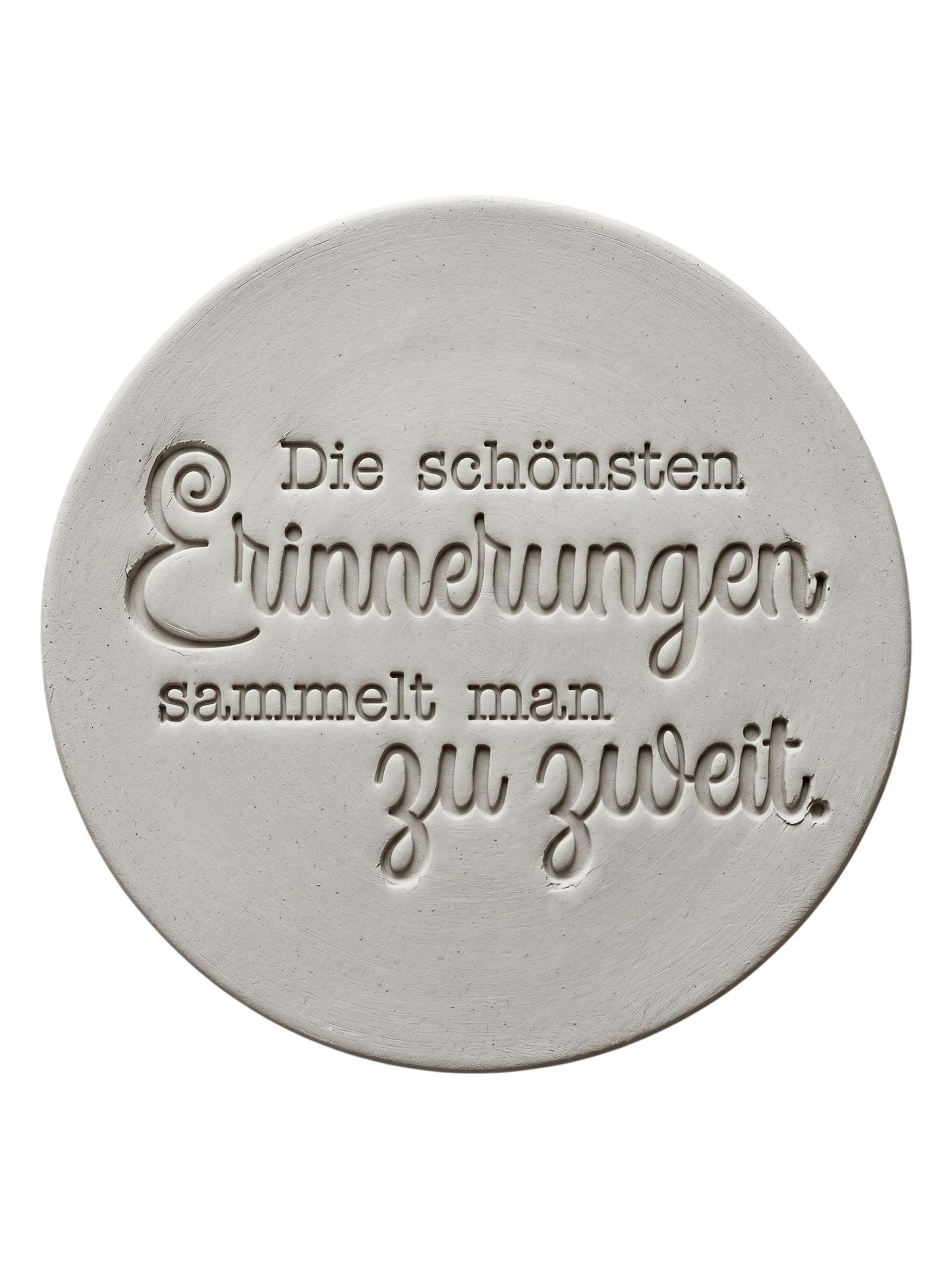 Präziser Stempelabdruck des romantischen Spruchs 'Die schönsten Erinnerungen sammelt man zu zweit' in hellem Ton. Detailreiches, sauberes Relief aus Schreibmaschinenschrift und Kalligrafie auf einer runden Tonplatte.