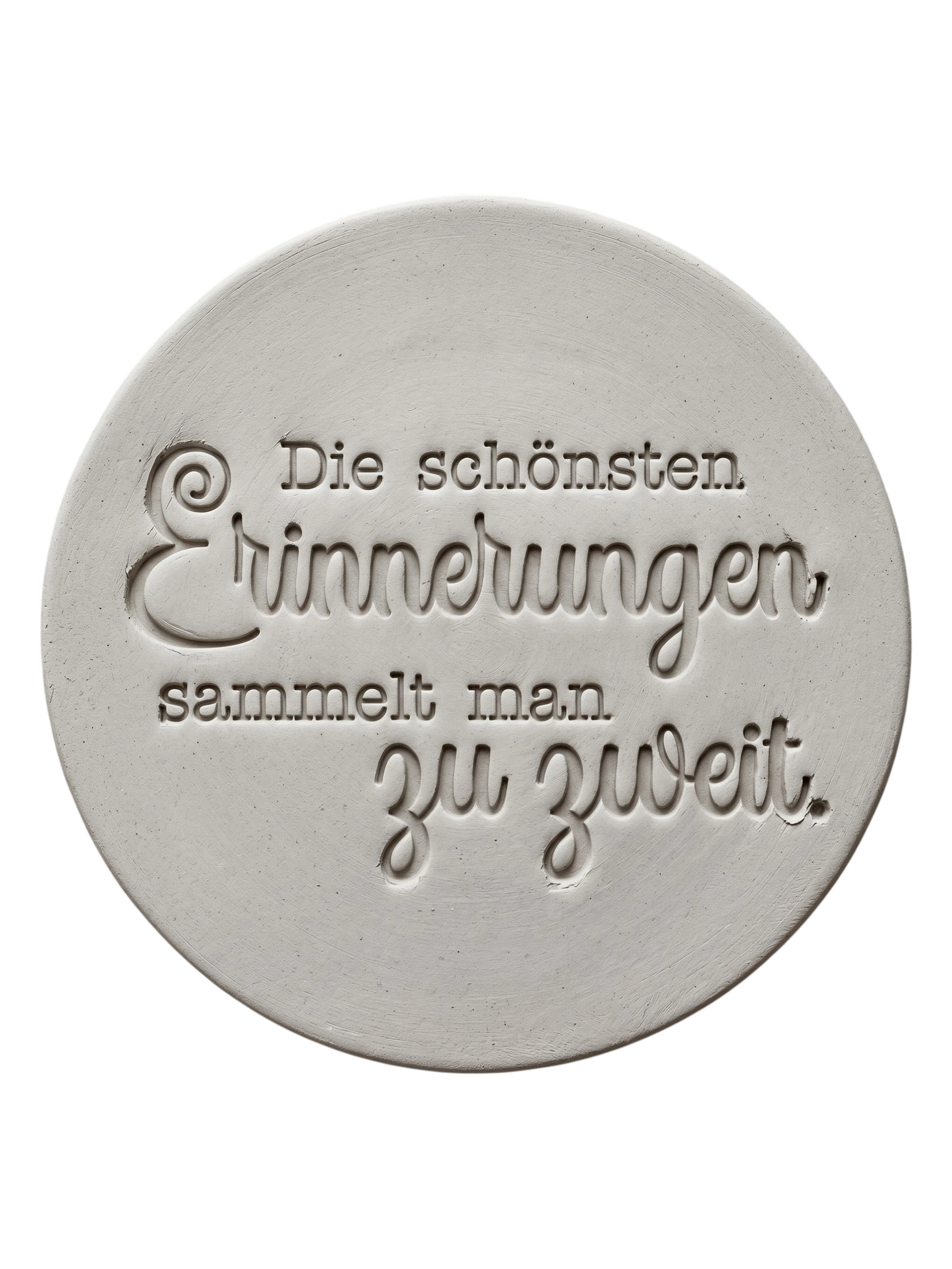 Präziser Stempelabdruck des romantischen Spruchs 'Die schönsten Erinnerungen sammelt man zu zweit' in hellem Ton. Detailreiches, sauberes Relief aus Schreibmaschinenschrift und Kalligrafie auf einer runden Tonplatte.