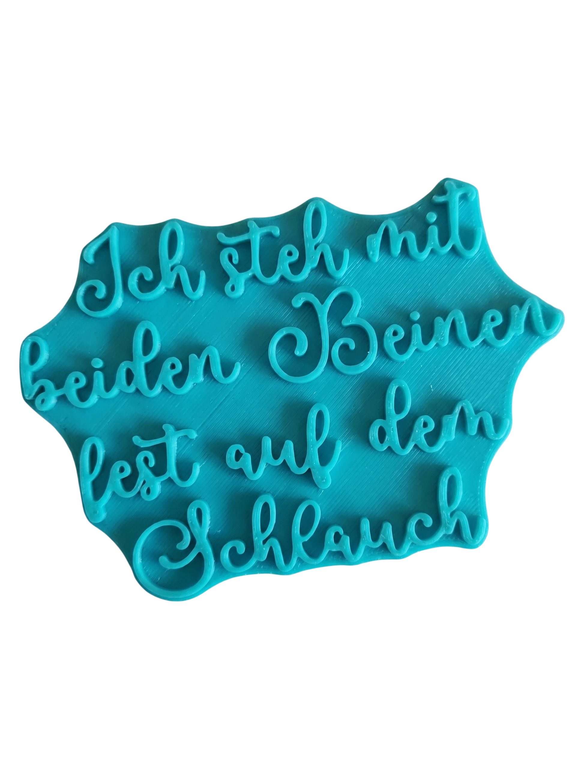 Blaugrüner Textstempel für Ton mit dem humorvollen Spruch 'Ich steh mit beiden Beinen fest auf dem Schlauch'. Hochwertiges Töpferzubehör für klare Prägungen.