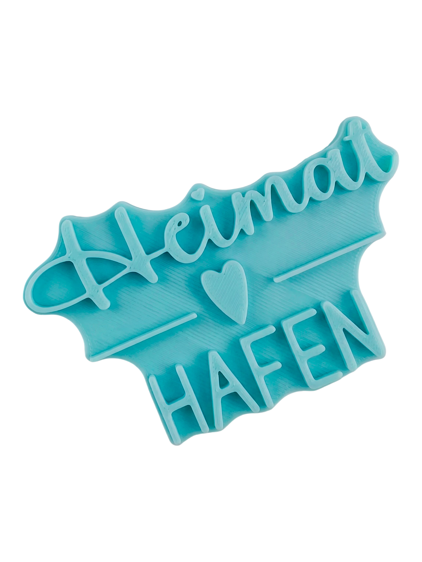Blaugrüner Textstempel für Ton mit dem Schriftzug 'Heimathafen' und Herz-Symbol. Hochwertiges Werkzeug für präzise Prägungen in Keramik und Ton.