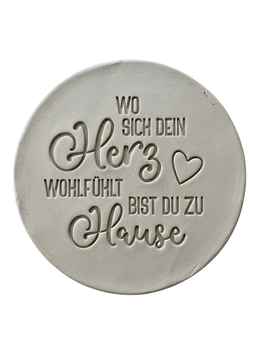 Präziser Abdruck im rohen Ton mit dem Spruch 'Wo sich dein Herz wohlfühlt bist du zu Hause'. Gestaltet mit einem MinseArt Keramikstempel. Detailreiche Töpfer-Idee für Türschilder oder dekorative Wandteller aus Keramik.