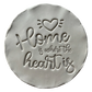 Präziser Abdruck im hellen Ton mit dem englischen Spruch 'Home is where the heart is'. Kreative Töpfer-Idee für Türschilder, Einzugsgeschenke oder dekorative Wandteller.