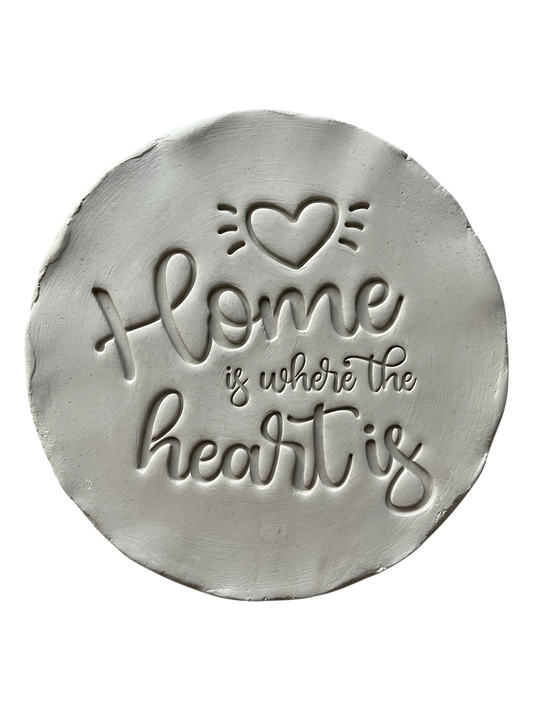 Präziser Abdruck im hellen Ton mit dem englischen Spruch 'Home is where the heart is'. Kreative Töpfer-Idee für Türschilder, Einzugsgeschenke oder dekorative Wandteller.