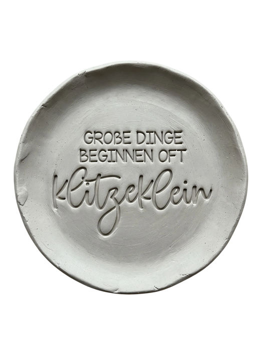 Handgemachte Töpfer-Idee mit dem MinseArt Textstempel: Spruch 'Große Dinge beginnen oft klitzeklein' eingestempelt in hellen Ton. Präziser Abdruck für Keramik-Anhänger und Geschenke zur Geburt oder Neuanfang.