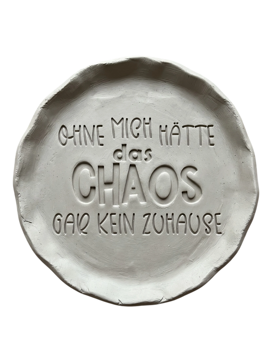 Detaillierter Abdruck im hellen Ton mit dem humorvollen Spruch 'Ohne mich hätte das Chaos gar kein Zuhause'. Kreative Töpfer-Idee für lustige Türschilder oder Wandteller.